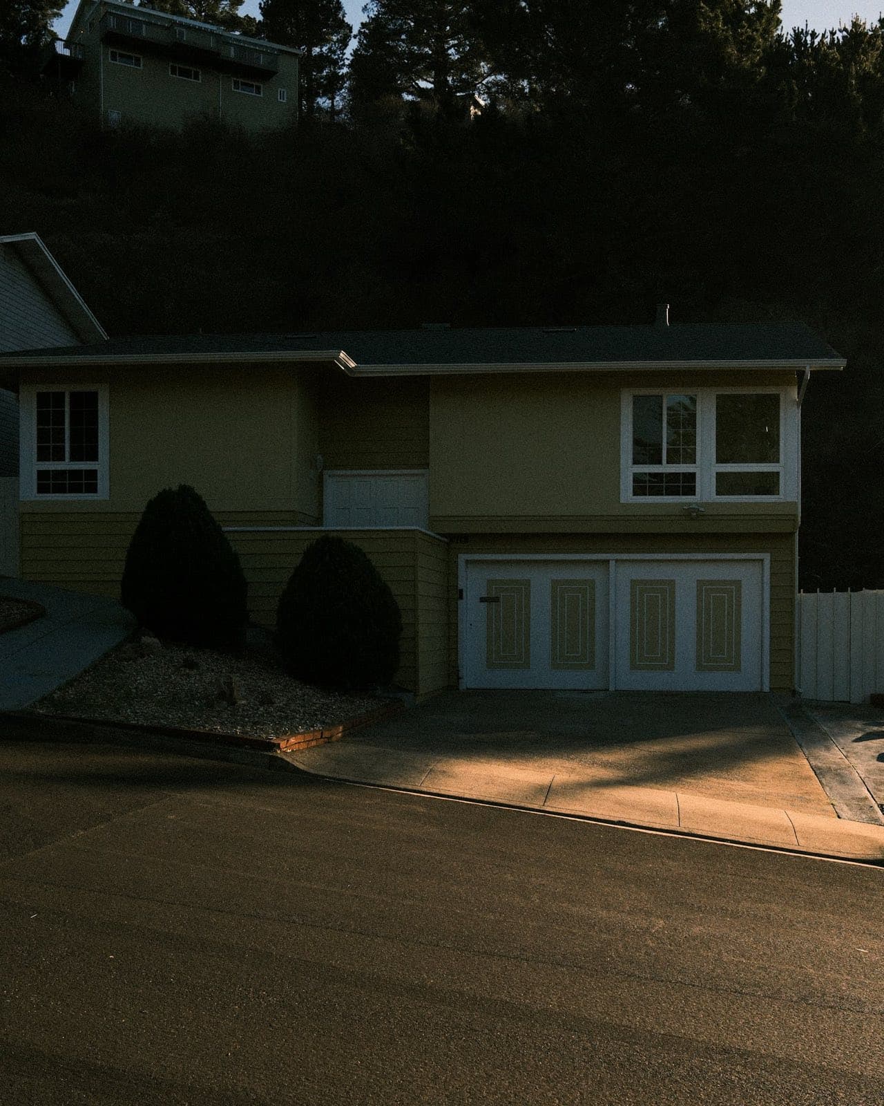 A suburban house with a white two-car garage door at sunset