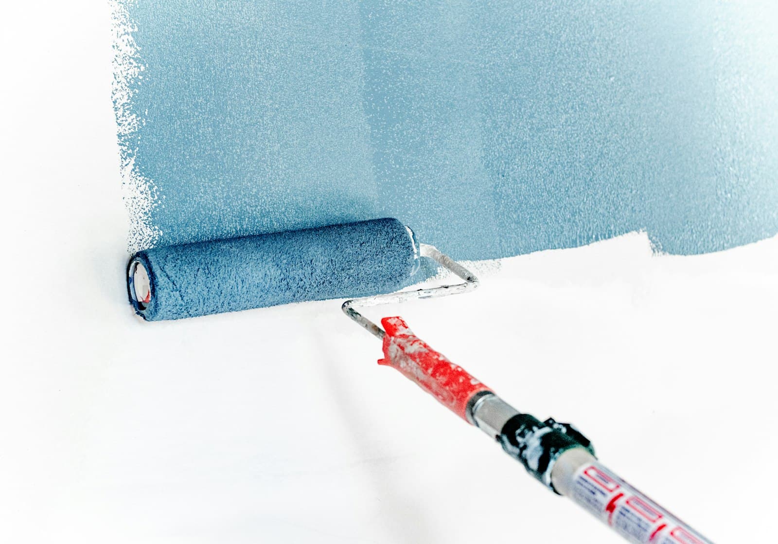 A roller painting a wall
